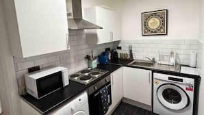 A compact kitchen with a microwave, stove, dishwasher, and washing machine. - London Flat Next to Central Line Tube Station (London)