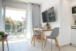 Una cocina moderna con horno empotrado, un comedor con mesa y sillas, y un ventanal con cortinas.