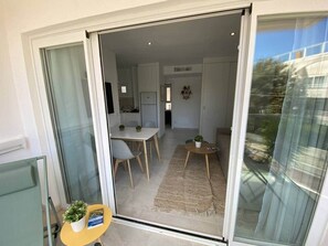 Un ambiente moderno con zona pranzo, cucina e una porta scorrevole in vetro che dà su un balcone.
