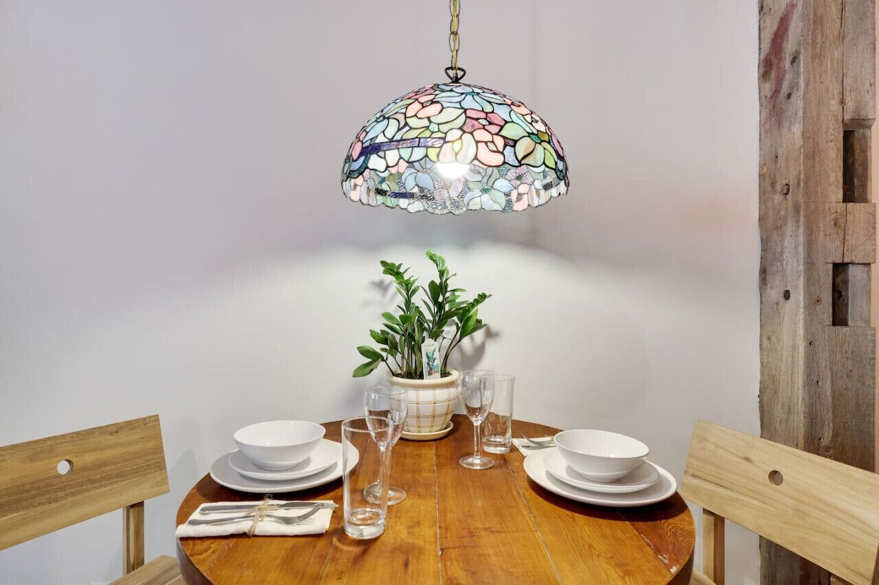 Een houten eettafel met witte borden, glazen en een plant in pot.