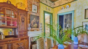 Un comedor con una mesa de madera, sillas y un jarrón grande con plantas verdes.