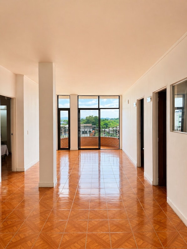 A spacious interior with a large window, a tiled floor, and a door leading to another room.