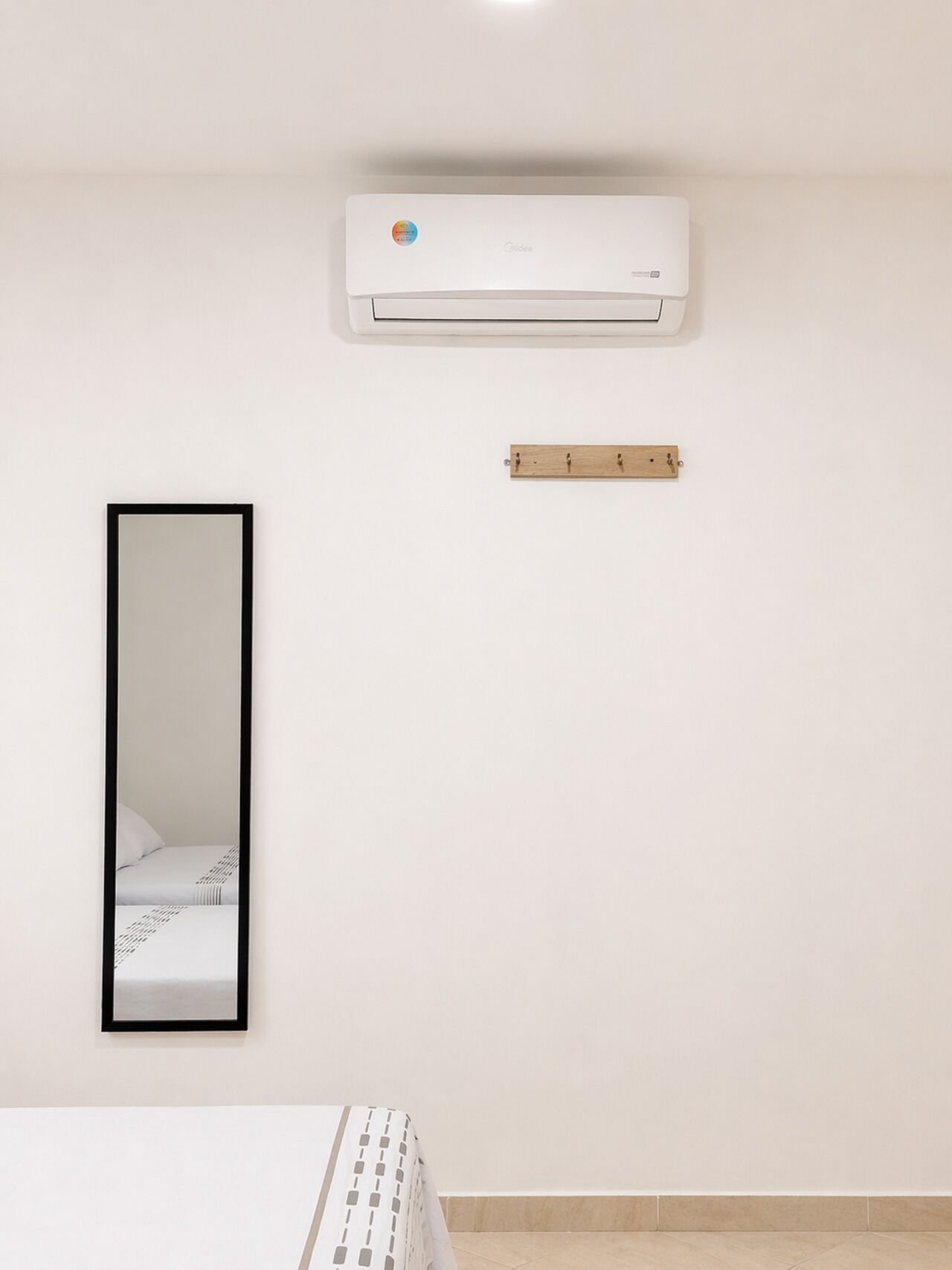 Une pièce comprenant un lit, un climatiseur fixé au mur, une étagère en bois et un miroir.