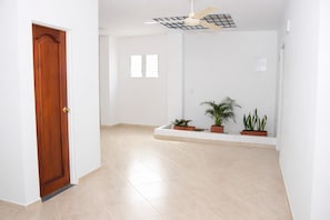 A hallway with a wooden door, a ceiling fan, and potted plants.