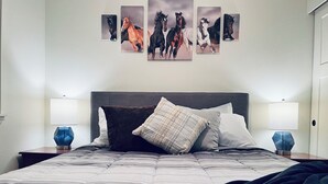 Un lit bien fait, avec une couette à rayures, une tête de lit sombre et deux lampes de chevet.