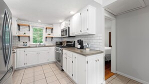 A modern kitchen with white cabinets, a stainless steel refrigerator, a microwave, and an oven. - Peaceful Oasis minutes to T.F. Green International Airport, Main Street & more (East Greenwich)