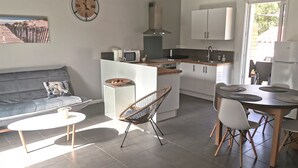 A modern kitchen with white cabinets, a built-in stove, and a dining area with a table and chairs.