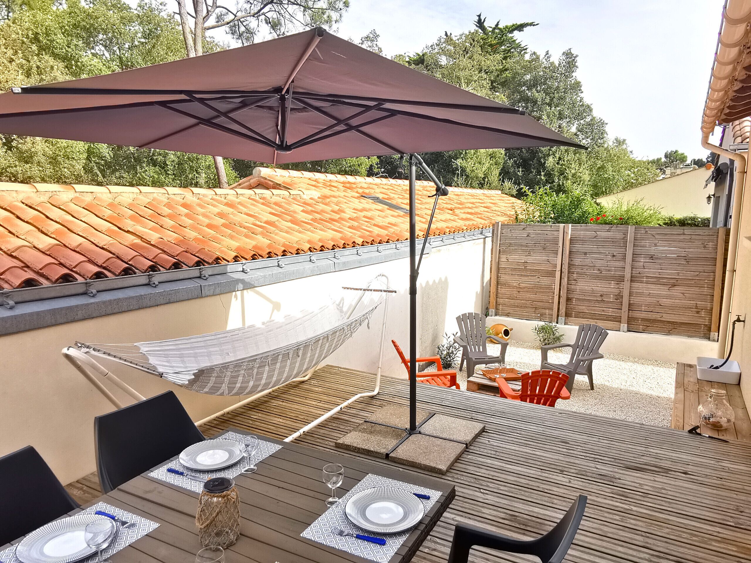 An outdoor patio with a table set for dining, a hammock, and outdoor seating.