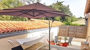 An outdoor patio with a table set for dining, a hammock, and outdoor seating.