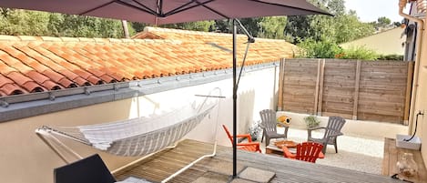 An outdoor patio with a table set for dining, a hammock, and outdoor seating.