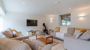 Een moderne woonkamer met een open haard, een flatscreen televisie en een comfortabele zithoek.