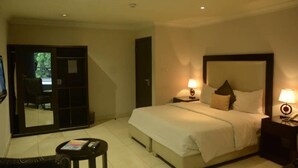 A hotel room with a bed, bedside lamps, a small table, and a chair. - Novel Suites And Resort (Jos)