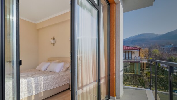 Un dormitorio con cama, mesita de noche y ventana con cortinas.