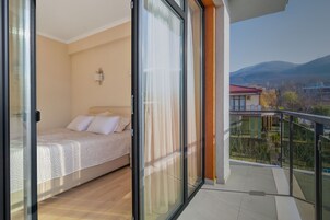 Un dormitorio con cama, mesita de noche y ventana con cortinas.