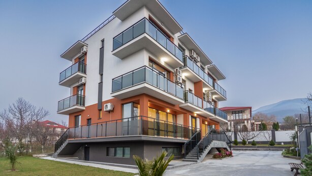 A multi-story residential building with balconies, a staircase, and a small garden area.