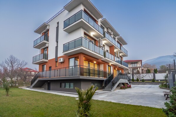 A multi-story residential building with balconies, a staircase, and a small garden area.