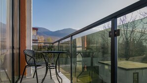A balcony with a glass railing, a table, and two chairs.