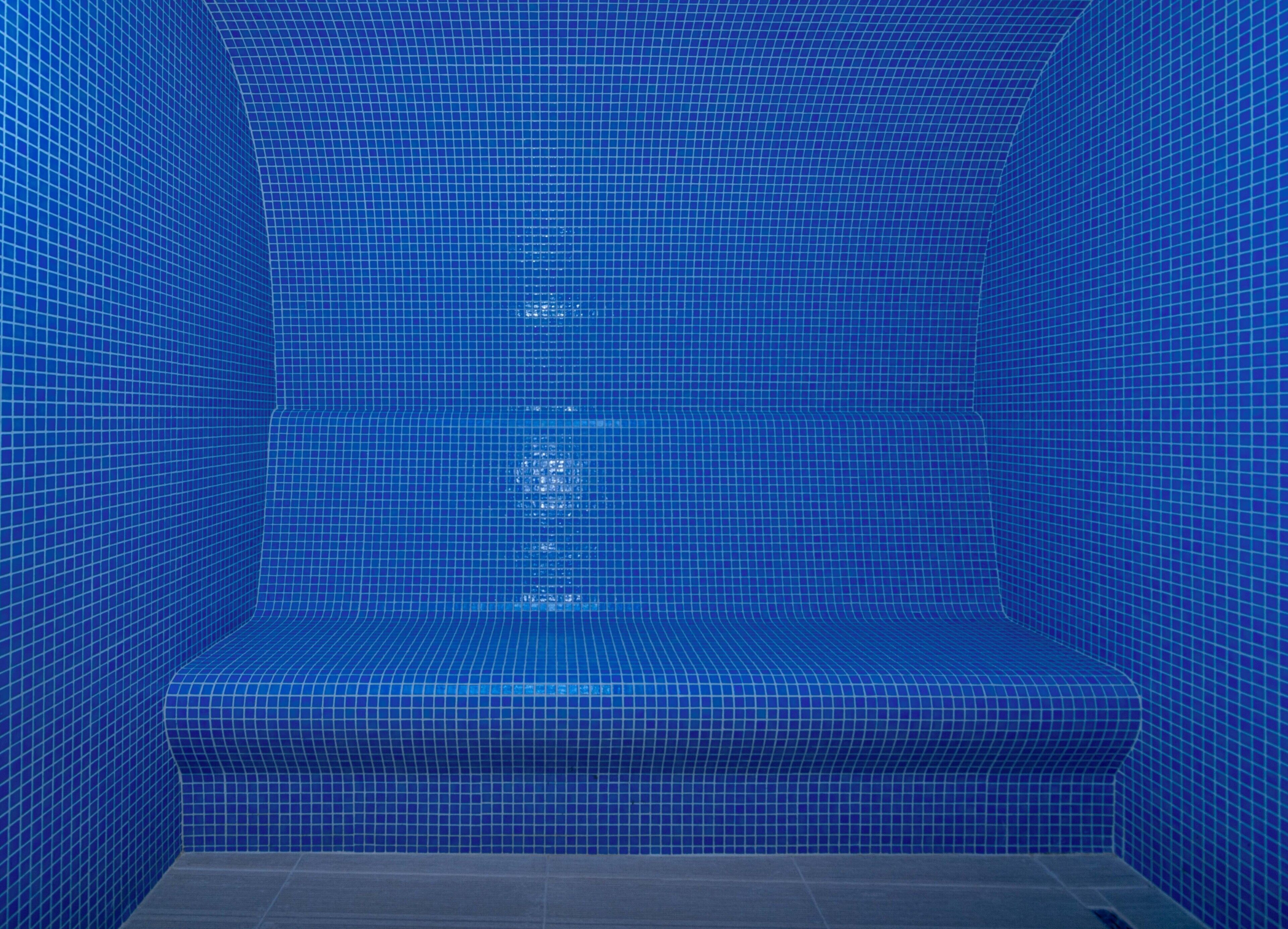 Une zone de douche aux carreaux bleus, avec un banc.