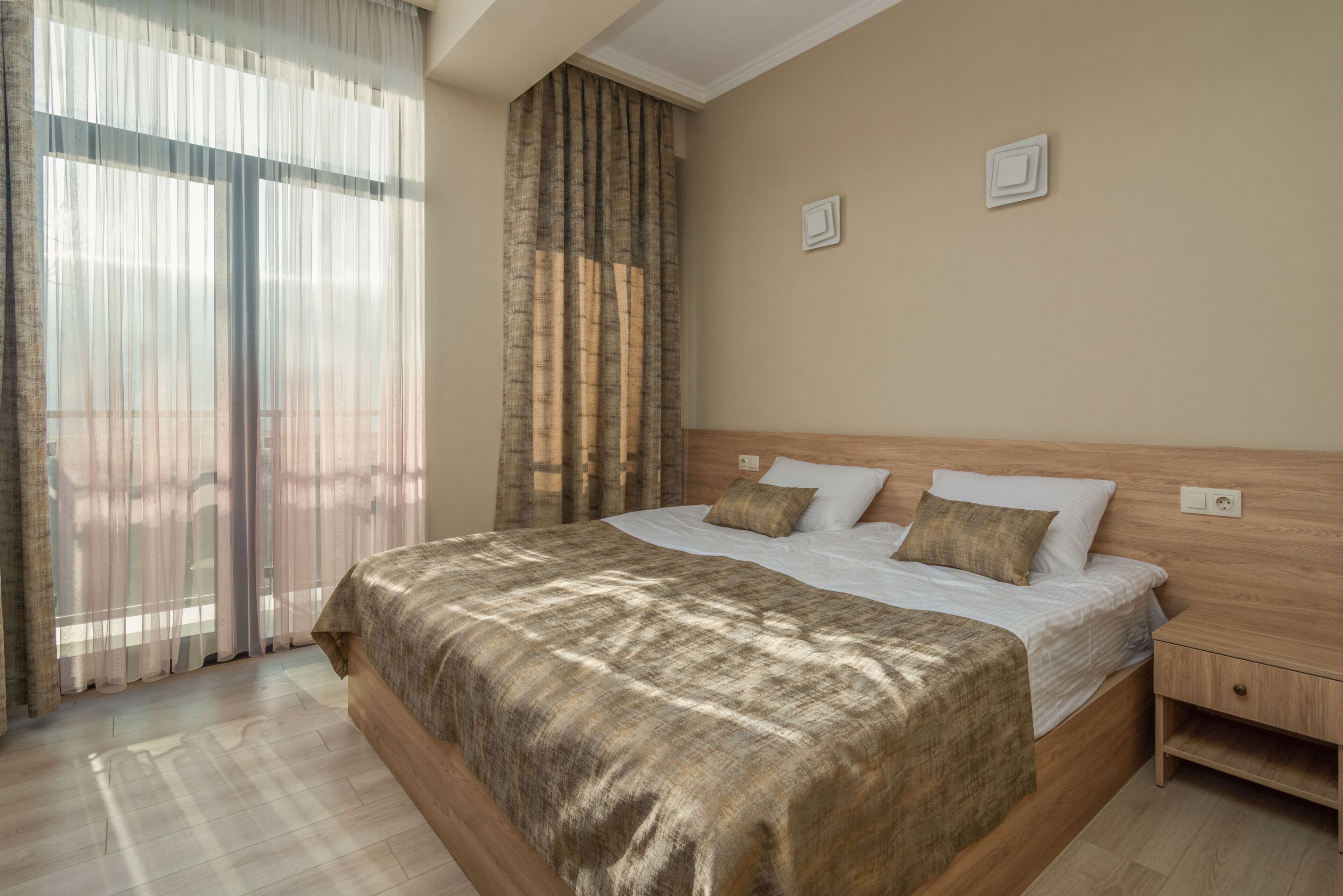 A bedroom with a large bed, wooden headboard, and a nightstand.