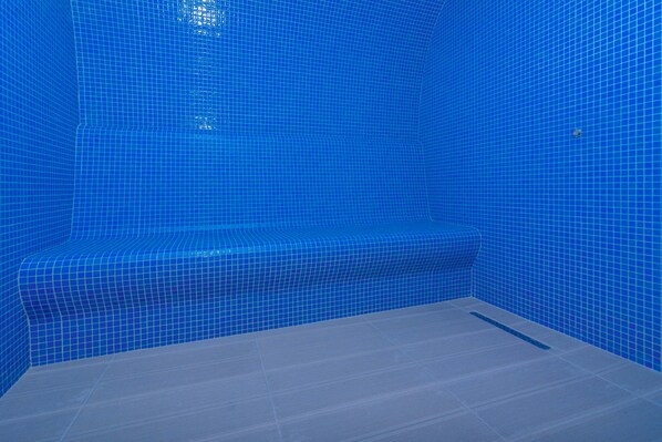 Un baño con paredes de azulejos azules y un banco.