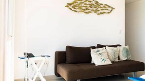 A modern living room with a brown sofa, a white coffee table, and a decorative wall piece. - Oceanfront apartment, swimming pool, automatic check-in (Guayaquil)