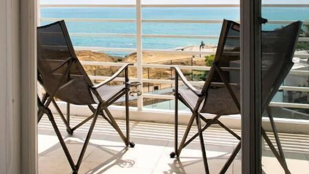 A balcony with two chairs facing a beach view. - Oceanfront apartment, swimming pool, automatic check-in (Guayaquil)