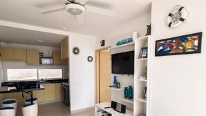 A modern living room with a sofa, a coffee table, a TV, and a bookshelf. - Oceanfront apartment, swimming pool, automatic check-in (Guayaquil)