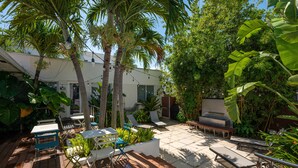 A patio area with outdoor seating, palm trees, and lush greenery. - CASA DEL MAR HOLLYWOOD (Hollywood)