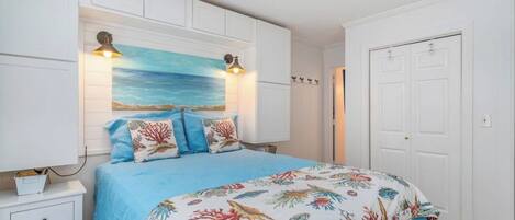 A bedroom with a bed, a nightstand, a wall-mounted lamp, and a door.