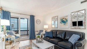 Ein Wohnzimmer mit einem schwarzen Ledersofa, einem weißen Couchtisch und blauen Vorhängen.