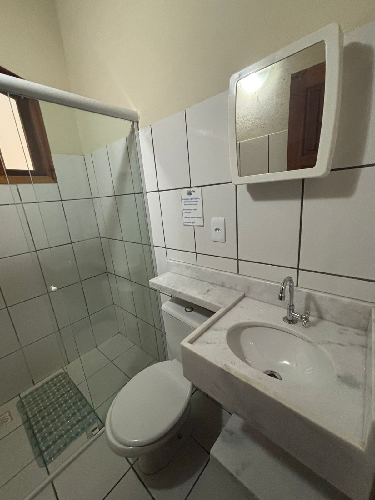 A bathroom with a toilet, sink, and mirror.
