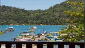 A coastal view with boats docked at a pier, surrounded by lush greenery. - Flats e suítes nativa (Paraty)