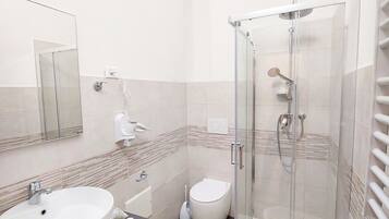Un baño moderno con un lavamanos grande, inodoro y ducha con mampara de vidrio.