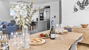 Un coin repas avec une table en bois mise pour le repas, comprenant une bouteille de vin, des verres et une assiette de nourriture.