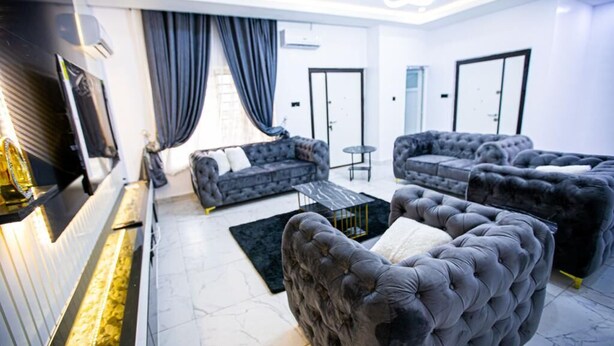 Un salon moderne comprenant un ensemble de canapés, une table basse et un téléviseur à écran plat fixé au mur.