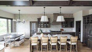 Une cuisine moderne avec un îlot central, des chaises en bois et des luminaires suspendus.