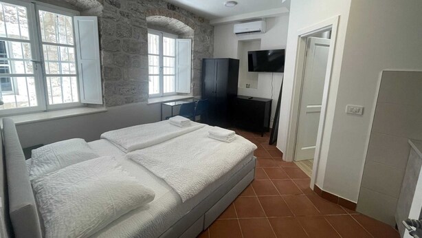 Une chambre à coucher avec un lit, un bureau, une chaise, un téléviseur et un mur en pierre.