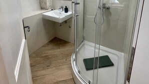 Une salle de bain moderne avec une douche à parois de verre, un meuble-lavabo avec un miroir et un mur d’accent en pierre.