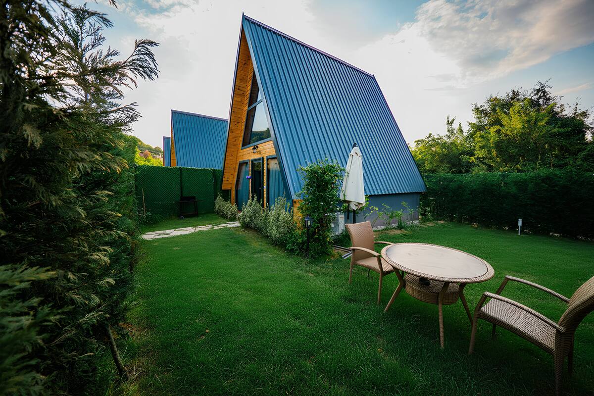 A modern building with a sloped roof, surrounded by a well-maintained lawn and a small table with chairs.