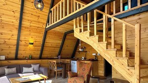 Un interior acogedor de madera con una escalera, un sofá, una mesa de comedor y una zona de cocina.