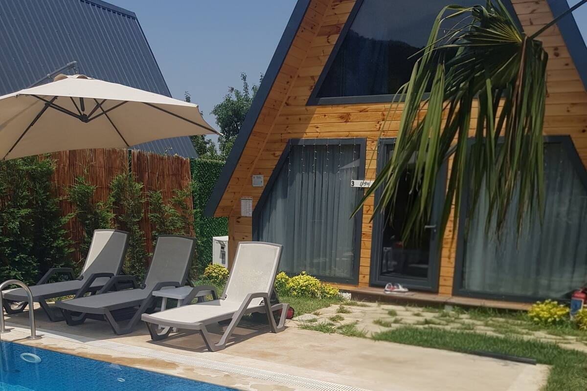 A swimming pool with lounge chairs, a large umbrella, and decorative lanterns.