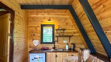 A cozy wooden cabin with a kitchen area featuring a refrigerator, sink, and wooden cabinets.