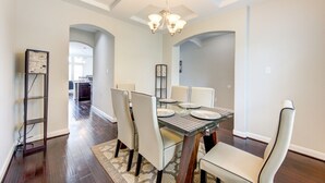 A dining area with a glass-top table, white chairs, and a chandelier. - 5-STARS HOST! Spacious 4-2.5 Pearland Clear Lake Friendswood. World Cup 2026 (Houston)