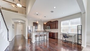 A spacious kitchen with dark wood flooring, a central island with chairs, and a dining area with a window. - 5-STARS HOST! Spacious 4-2.5 Pearland Clear Lake Friendswood. World Cup 2026 (Houston)