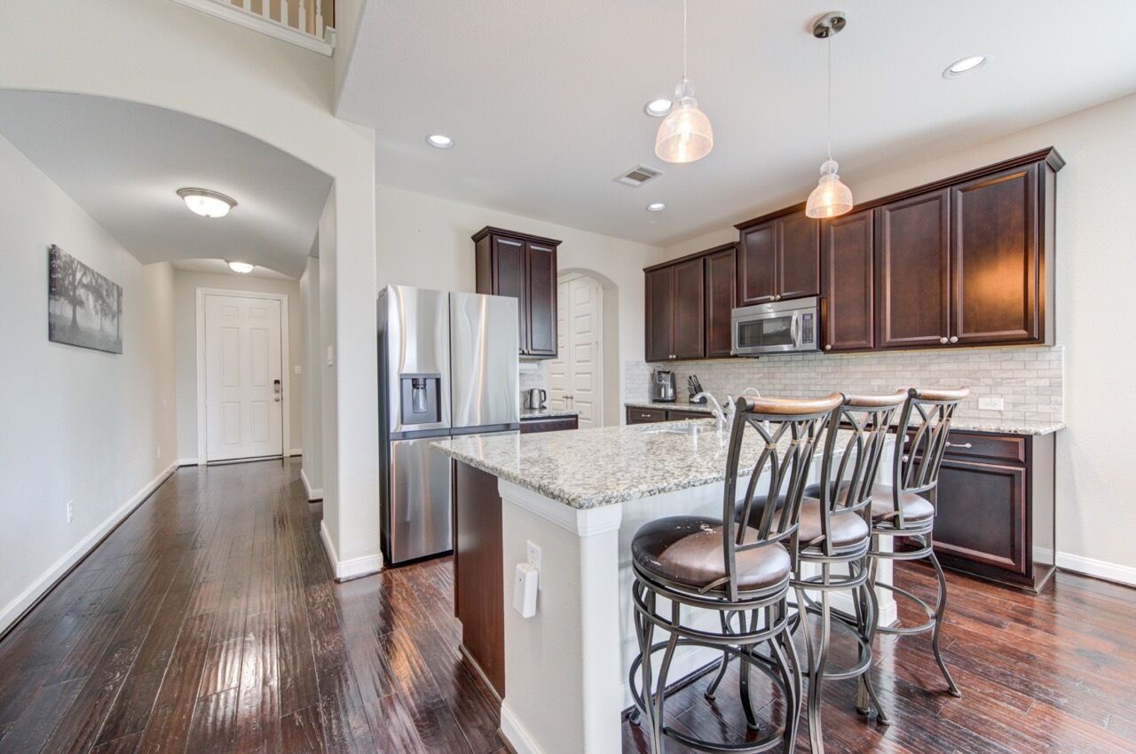 A spacious kitchen with dark wood cabinets, stainless steel appliances, and a central island with bar stools.