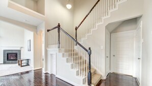A spacious living room with a hardwood floor, a fireplace, and a staircase with white railings and dark wood balusters. - 5-STARS HOST! Spacious 4-2.5 Pearland Clear Lake Friendswood. World Cup 2026 (Houston)