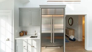 A modern kitchen with a stainless steel refrigerator, white cabinetry, and a built-in oven. - Summer Living! Nantucket Island Home with Pool, 6 bedrooms, AC, amenities (Nantucket)