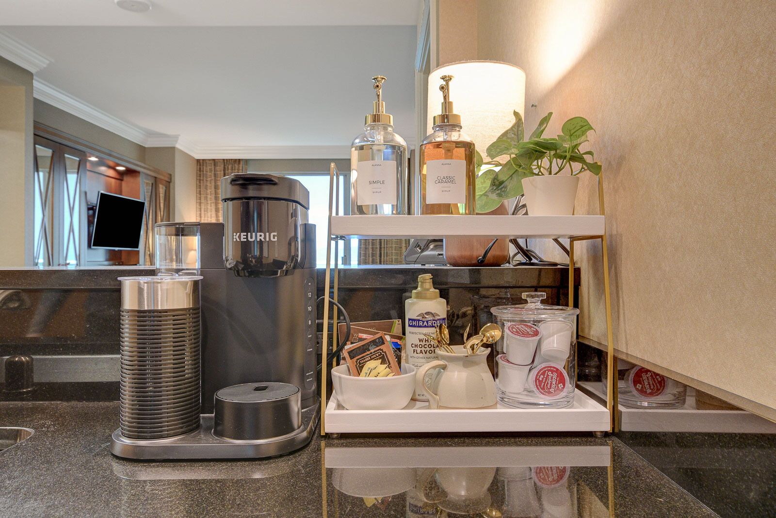 A kitchenette with a Keurig coffee maker, a water dispenser, and a shelf with various kitchen items.