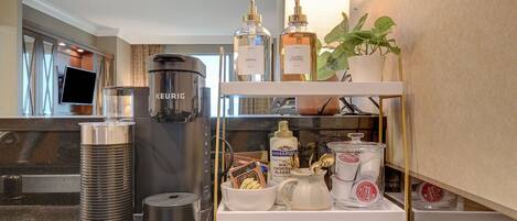 A kitchenette with a Keurig coffee maker, a water dispenser, and a shelf with various kitchen items.