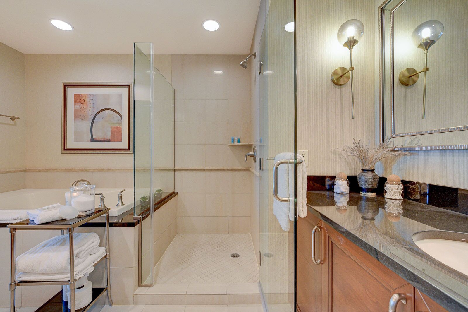 A modern bathroom with a glass-enclosed shower, a vanity with a large mirror, and a sink.